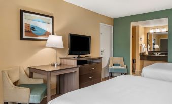 a hotel room with a bed , desk , and tv , along with a chair and lamp at Best Western Space Shuttle Inn