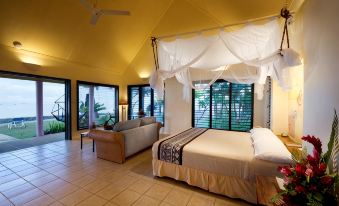 a spacious bedroom with a large bed and a couch in the corner , creating a cozy atmosphere at Fiji Hideaway Resort and Spa
