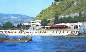 a beach scene with a group of people enjoying their time on the sandy shore at Hotel la Giara