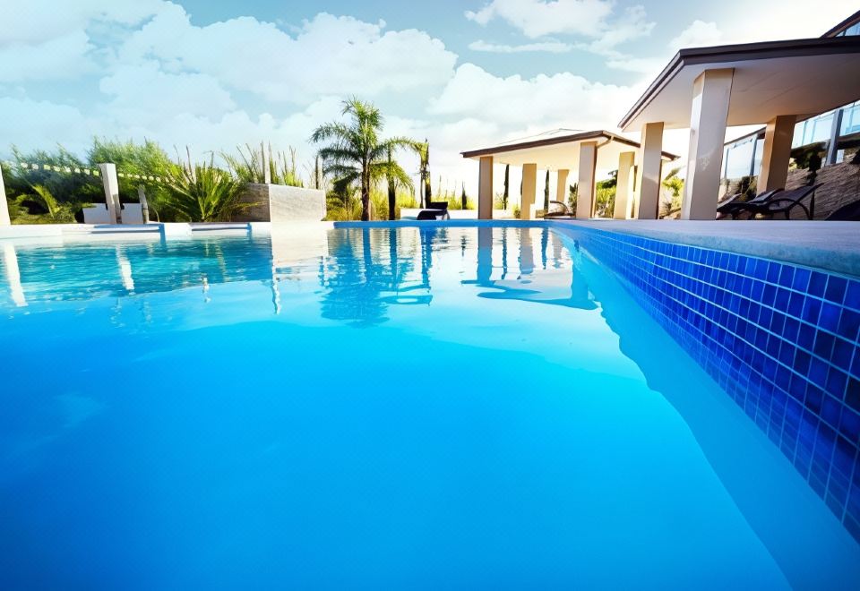 a large blue swimming pool surrounded by a house , with several lounge chairs and umbrellas placed around it at Swan River Hotel