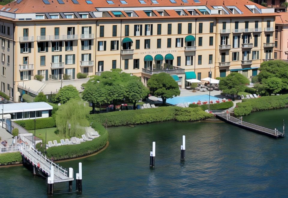 aerial view of a large apartment complex situated next to a body of water , with a dock extending into the lake at Grand Hotel Menaggio