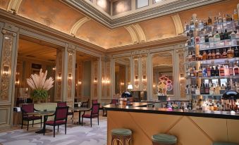 a grand bar area with a wooden counter , multiple stools , and a large mirror on the wall at Grand Hotel Et des Palmes