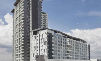 a tall , modern apartment building with a blue sign on the side , situated in a city setting at Citadines DPulze Cyberjaya