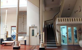 a large room with a staircase leading to the second floor , and a couch in the corner at Plaza Hotel