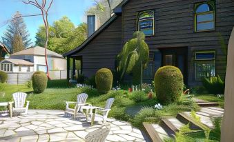 a wooden house surrounded by a lush green garden , with several chairs placed in front of it at The Little Inn of Bayfield