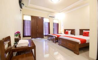 a hotel room with two beds , a television , and a door leading to a bathroom at RedDoorz Syariah @ Jalan Dieng
