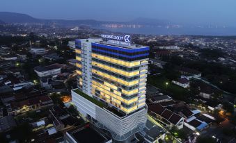 a large , modern building with a blue and white exterior is illuminated at night , surrounded by other buildings and a cityscape at Golden Tulip SpringHill Lampung