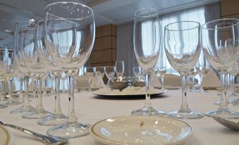a dining table set with wine glasses and a white plate , ready for a meal at Hotel Albufera