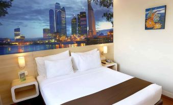 a bed with white pillows and a brown blanket is in a room with a large city skyline mural on the wall at Citihub Hotel @Kediri