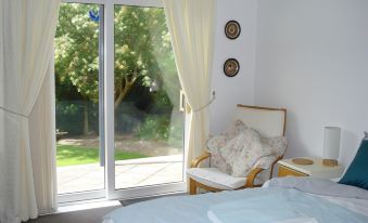 a cozy bedroom with a large window overlooking a garden , featuring a bed and a chair at Wildwinds