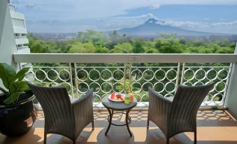 a balcony overlooking a beautiful view of a mountain , with two chairs and a table placed on it at Royal Ambarrukmo Yogyakarta