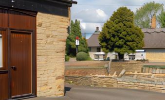 a brick building with a wooden door and a red traffic light on the side of the building at Church Farm Lodge