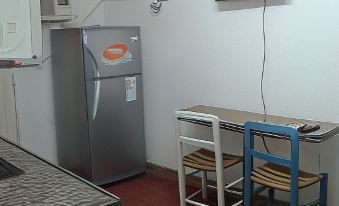 a small kitchen area with a refrigerator , microwave , and dining table , as well as a tv mounted on the wall at Alquimia