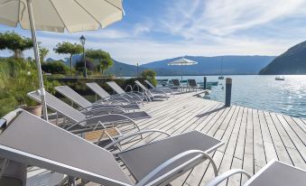 a wooden deck overlooking a body of water , with several lounge chairs and umbrellas placed along the deck at Abbaye de Talloires