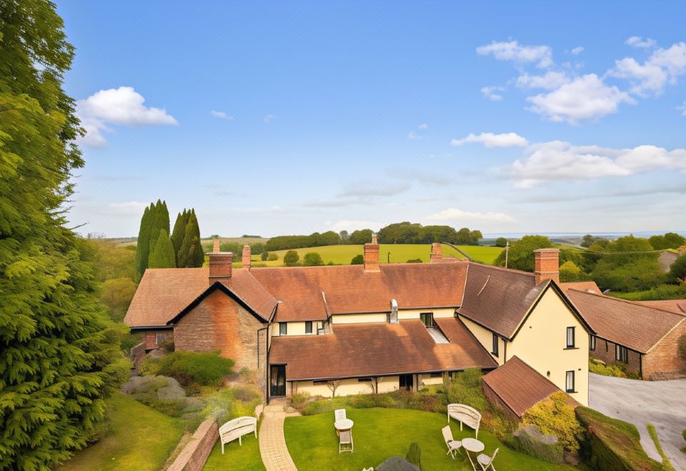 an aerial view of a large brick house surrounded by a lush green lawn , with trees and grass in the background at Castle of Comfort Hotel