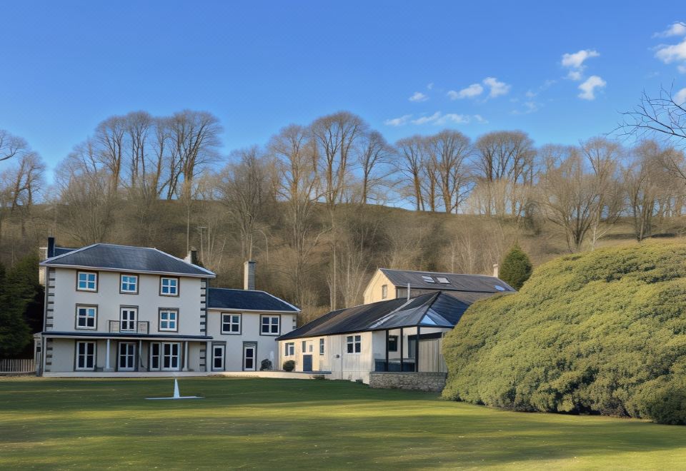 a group of buildings are situated on a green field with trees in the background at Lovelady Shield Country House Hotel