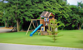 a wooden playground with a slide and other play equipment , surrounded by green grass and trees at Grand Caporal Hotel