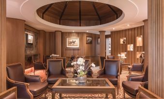 a cozy living room with wooden paneling , a fireplace , and several chairs arranged around a coffee table at Galgorm