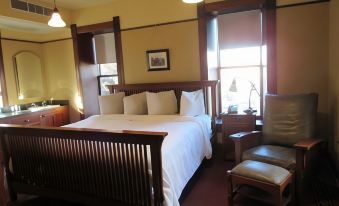a large bed with white linens is in a room with wooden furniture and lamps at Midland Railroad Hotel