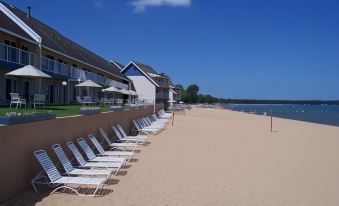 a sandy beach with several lounge chairs and umbrellas , as well as a row of buildings in the background at Pinestead Reef Resort