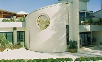 a modern building with a curved facade and large windows , surrounded by greenery and a driveway at Hotel Astoria