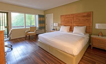 a large , well - made bed with white linens is in a hotel room with wooden floors and a window at General Butler State Resort Park
