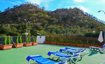 a rooftop deck with several blue lounge chairs and a view of the mountains in the distance at Hotel Maya Alicante