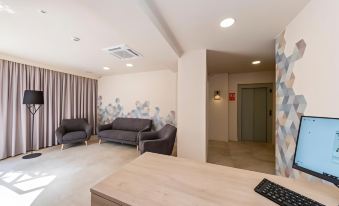 a modern living room with two couches , a dining table , and a tv . also a kitchenette in the room at Hotel Victori