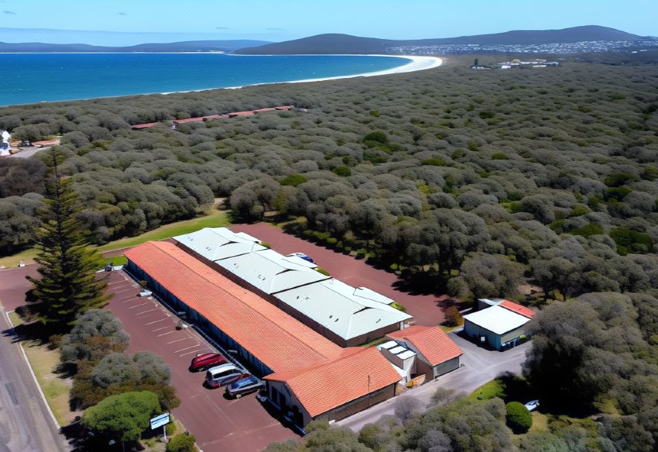 a large building with a red roof is surrounded by trees and overlooks a body of water at Emu Point Motel