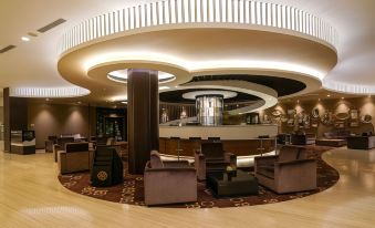 a hotel lobby with a large curved ceiling , multiple couches , and chairs arranged around the area at Java Heritage Hotel Purwokerto