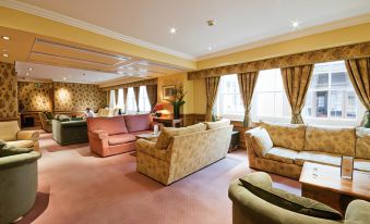 a living room with multiple couches and chairs arranged in various positions , creating a cozy atmosphere at Villiers Hotel