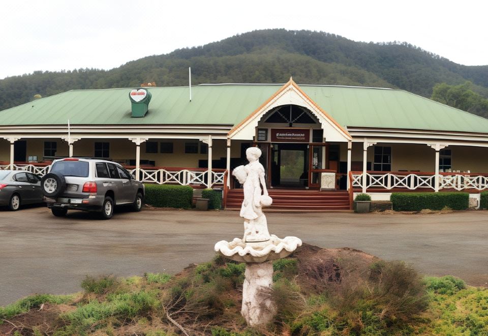 a building with a green roof and white columns is shown in front of a mountain at Bestbrook Mountain Farmstay