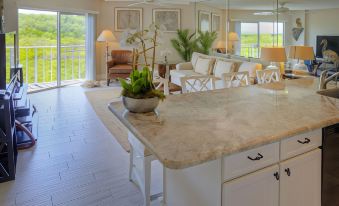 a spacious living room with a large white couch and chairs , as well as a dining area with a table and chairs at Ocean Pointe Suites at Key Largo