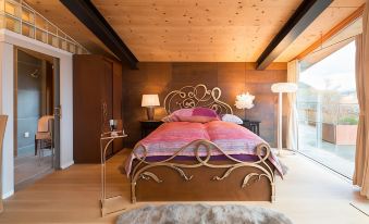 a cozy bedroom with a wooden ceiling , a large bed with a gold headboard , and a furry rug on the floor at The View
