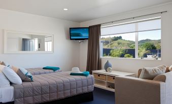 a hotel room with two beds , a television , and a window overlooking a beautiful view at Motel Oasis