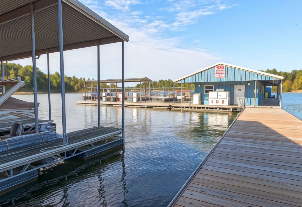 a dock with a boat docked at a pier , surrounded by water and trees , under a clear blue sky at Rough River DAM State Resort Park