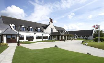 a large white building with a black roof and many windows is surrounded by grass and trees at Lancaster House Hotel