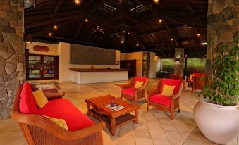 a spacious living room with wooden furniture , including couches , chairs , and a dining table , as well as a bar area at Finna Golf & Country Club