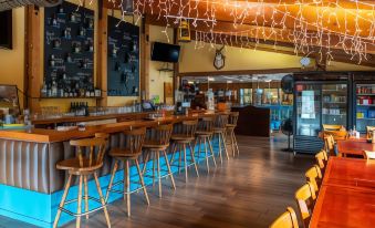 a bar area with wooden floors , several stools , and a television mounted on the wall at Yosemite Westgate Lodge