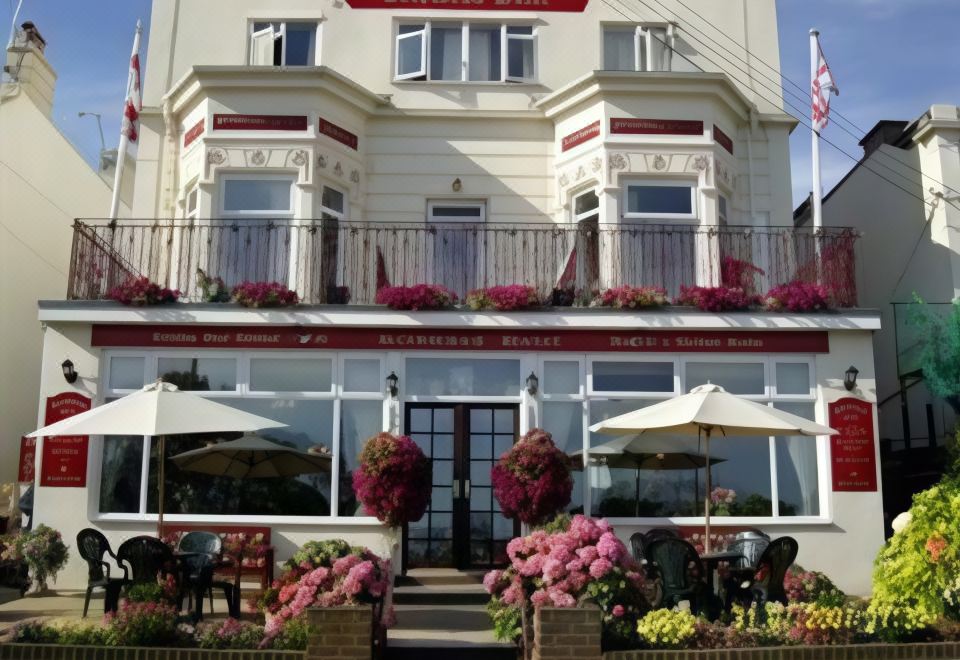 "a white building with red lettering and balconies , flowers , and a sign that reads "" restaurant france ""." at Richmond Hotel