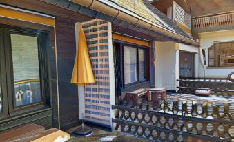 a small house with a yellow umbrella on the porch , surrounded by potted plants and potted flowers at Hotel Faller