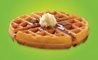 a waffle with butter and syrup on it , sitting on a green background with a gold border at La Quinta Inn & Suites by Wyndham Bannockburn-Deerfield
