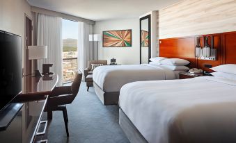 a modern hotel room with two beds , a desk , and a large window offering a view of the city at Marriott Albuquerque