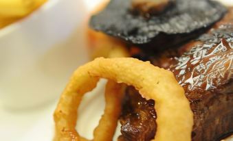 a close - up view of a bowl filled with food , including a piece of fried chicken and onion rings at Sturdys Castle