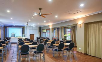 a large conference room with rows of chairs arranged in a semicircle , and a ceiling fan above the room at Oxford Lodge Vryheid