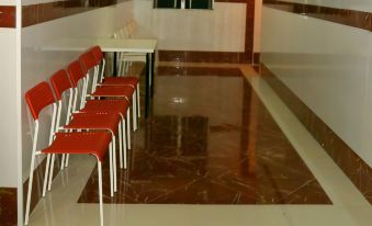 There is a row of benches in an empty room with a white tiled floor and red chairs at Delta Lounge