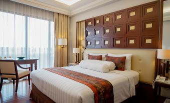 a large bed with a white and red blanket is in a room with wooden headboard , lamps , and lamps on either side at The Sunan Hotel Solo