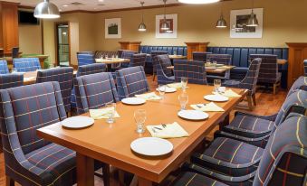 a dining room with a long wooden table and several chairs , all set for a meal at Wyndham Garden Manassas