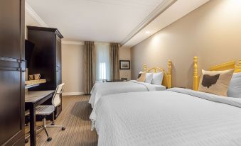 a hotel room with two beds , a desk , and a window , decorated in white and yellow colors at The Aurora Inn Hotel and Event Center