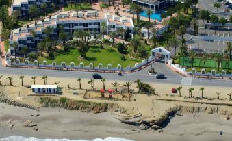 an aerial view of a beachfront resort with multiple buildings , trees , and a road near the water at Parador de Mojacar